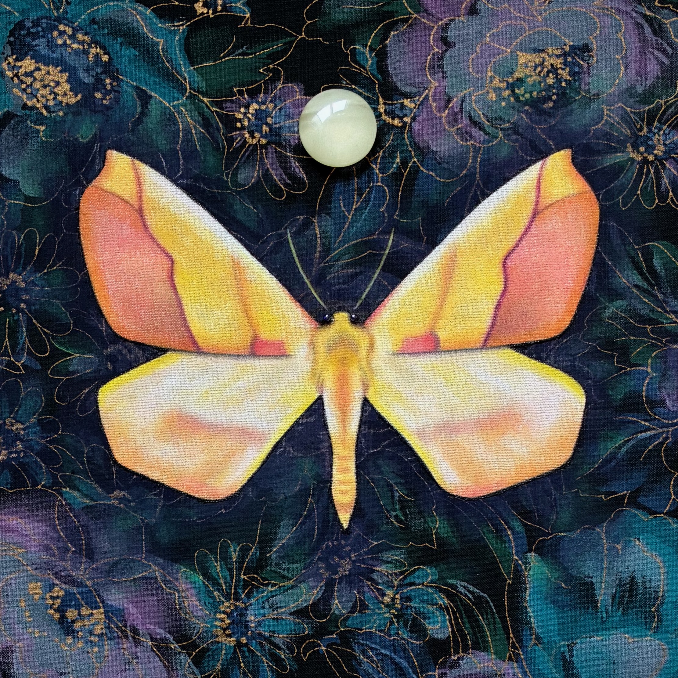A traditional mixed media art piece of a sharp-lined yellow moth against a purple and blue pattern fabric background
